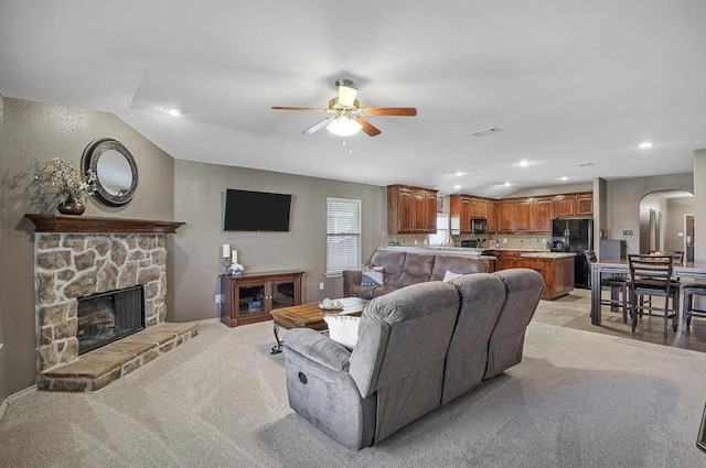 carpeted living room featuring a fireplace, lofted ceiling, and ceiling fan