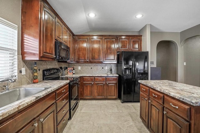 kitchen featuring sink, backsplash, black appliances, and lofted ceiling