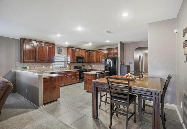 kitchen with black appliances, backsplash, a center island, and kitchen peninsula