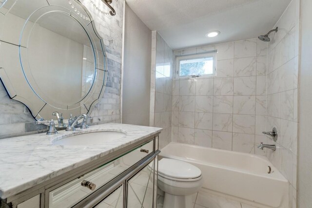 full bathroom featuring tiled shower / bath combo, toilet, and vanity