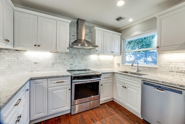 kitchen with white cabinets, appliances with stainless steel finishes, wall chimney exhaust hood, sink, and backsplash