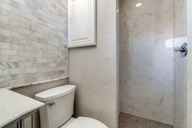 bathroom featuring toilet, vanity, and a tile shower