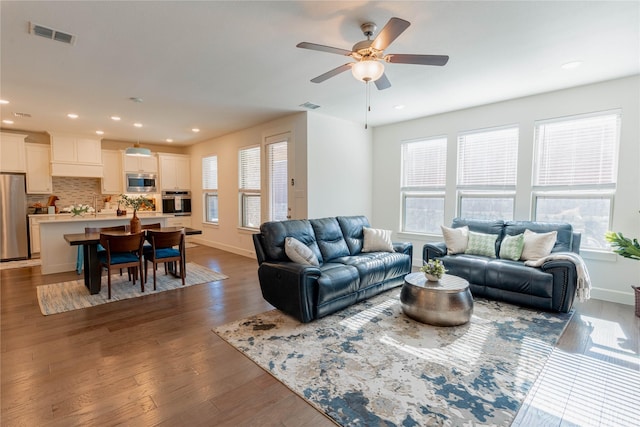 living room with dark hardwood / wood-style floors, a wealth of natural light, and ceiling fan