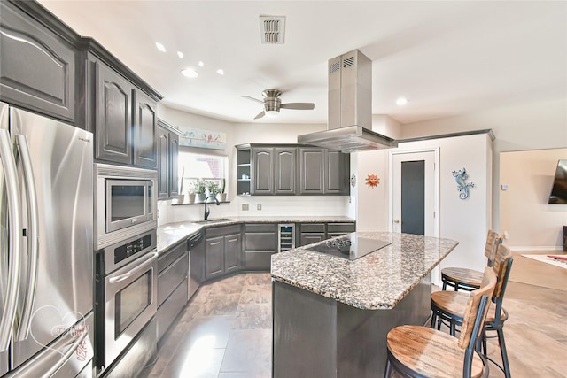 kitchen featuring appliances with stainless steel finishes, a breakfast bar area, island exhaust hood, a center island, and sink