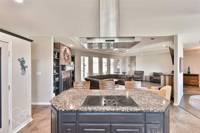 kitchen featuring stovetop, a center island, island exhaust hood, and stone counters