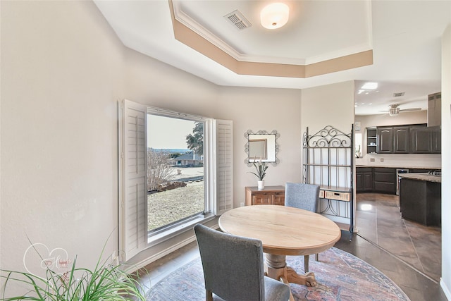 dining space with a tray ceiling, ornamental molding, and ceiling fan