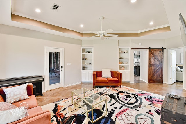 living room with light tile patterned floors, ceiling fan, a raised ceiling, a barn door, and built in features