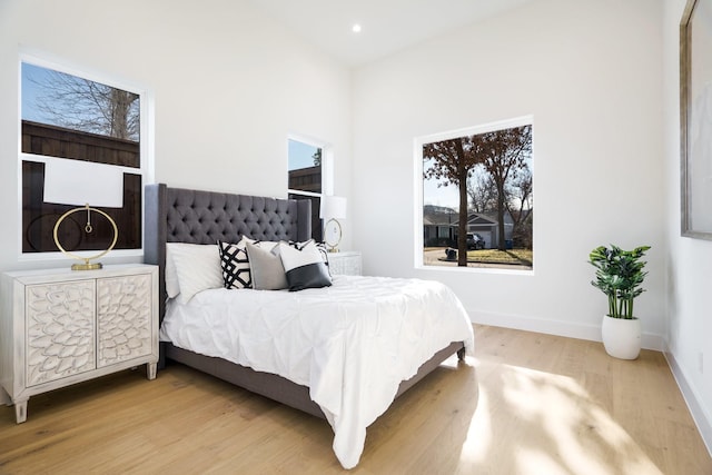 bedroom featuring light wood-type flooring and a towering ceiling