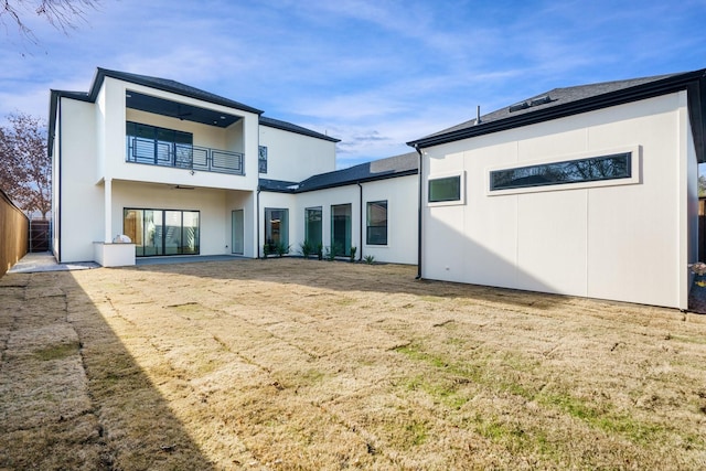 back of property featuring a balcony and a yard