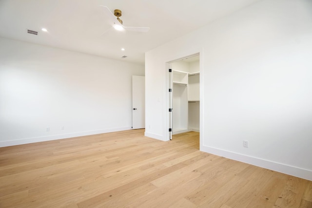 unfurnished bedroom featuring ceiling fan, light wood-type flooring, a closet, and a spacious closet