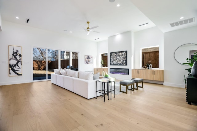 living room featuring ceiling fan, light wood-type flooring, and plenty of natural light