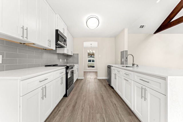 kitchen featuring appliances with stainless steel finishes, tasteful backsplash, white cabinetry, sink, and vaulted ceiling