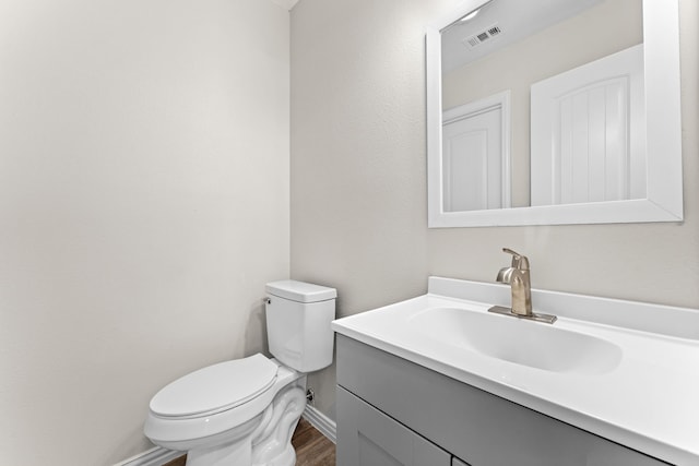 bathroom featuring wood-type flooring, toilet, and vanity