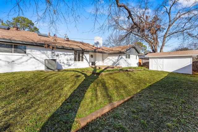 back of property featuring a yard and a storage shed