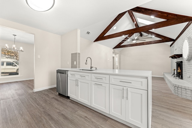 kitchen with stainless steel dishwasher, sink, decorative light fixtures, white cabinets, and lofted ceiling with beams