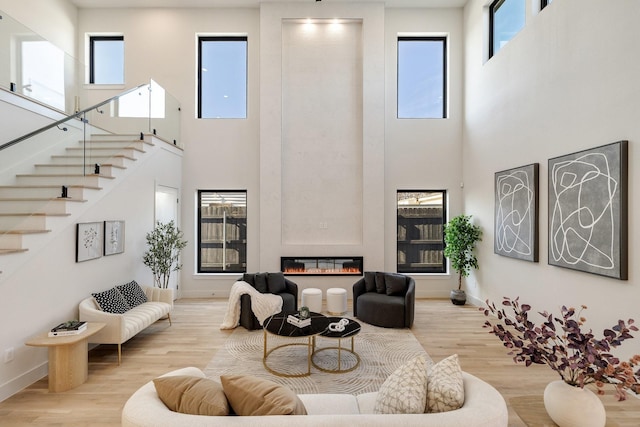 living room with plenty of natural light, a fireplace, a high ceiling, and light wood-type flooring