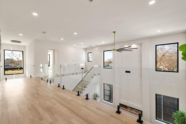 interior space with ceiling fan, a large fireplace, and light wood-type flooring