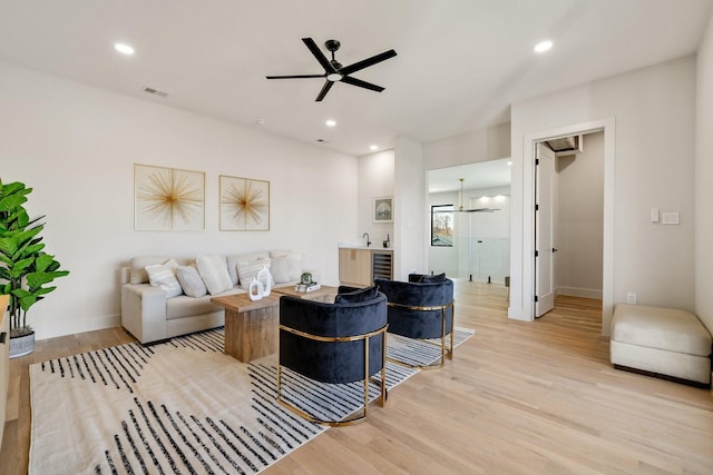 living room with wine cooler, light hardwood / wood-style floors, and ceiling fan