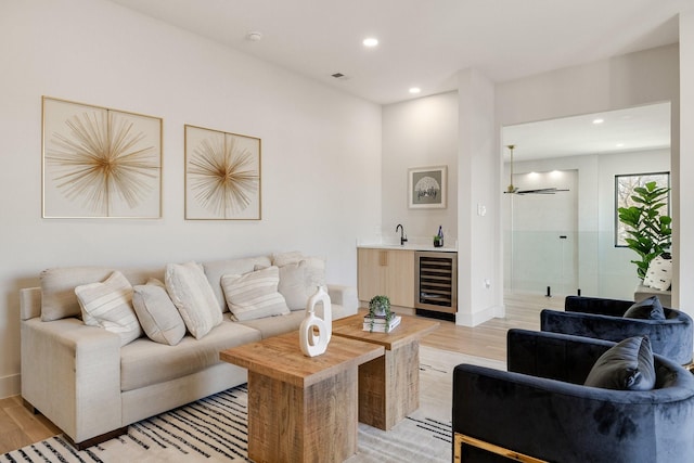 living room featuring wet bar, wine cooler, and light wood-type flooring