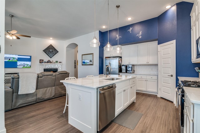 kitchen featuring white cabinets, a kitchen island with sink, appliances with stainless steel finishes, and sink