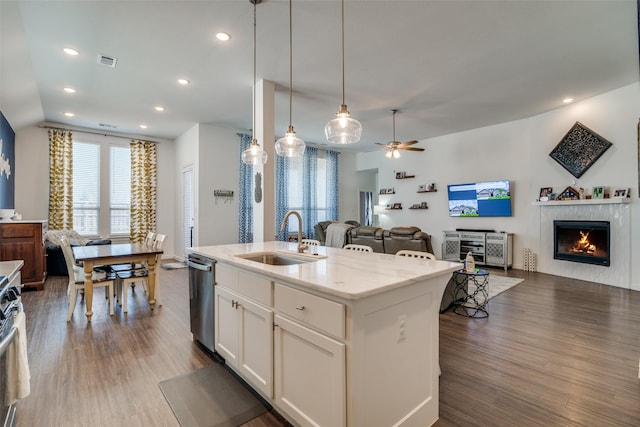 kitchen featuring sink, white cabinetry, light stone counters, pendant lighting, and a kitchen island with sink