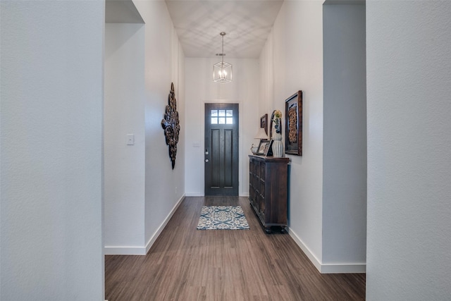 entryway with an inviting chandelier and dark wood-type flooring