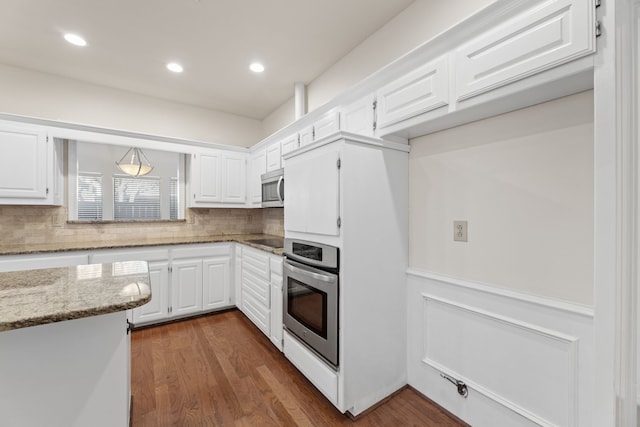 kitchen with light stone countertops, white cabinetry, appliances with stainless steel finishes, and dark hardwood / wood-style flooring