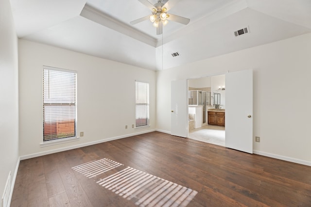 empty room with ceiling fan, a raised ceiling, and wood-type flooring