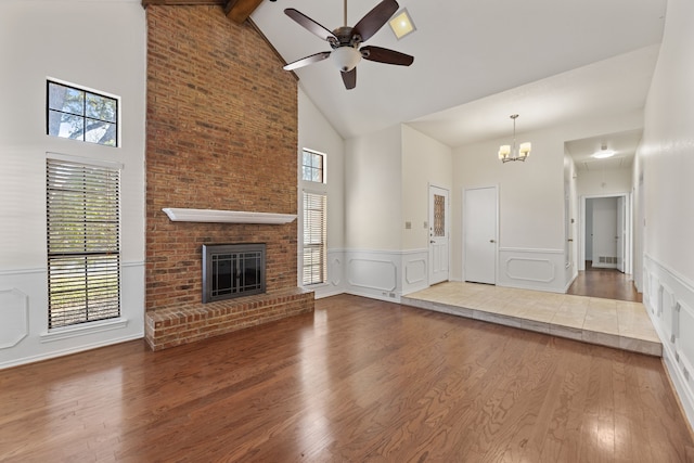 unfurnished living room with hardwood / wood-style floors, a fireplace, high vaulted ceiling, beam ceiling, and ceiling fan