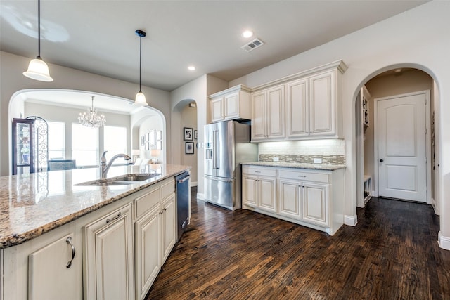 kitchen featuring light stone countertops, a kitchen island with sink, sink, decorative light fixtures, and stainless steel appliances