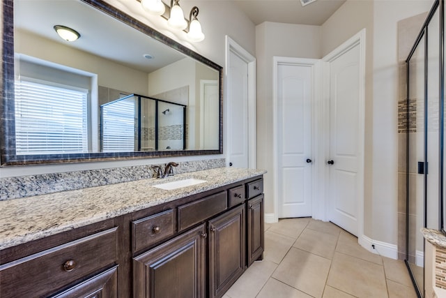 bathroom featuring tile patterned floors, a shower with door, and vanity