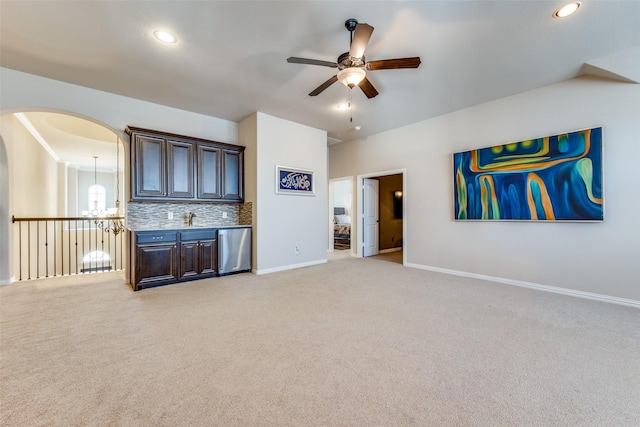 kitchen with decorative backsplash, dark brown cabinetry, light carpet, and ceiling fan with notable chandelier