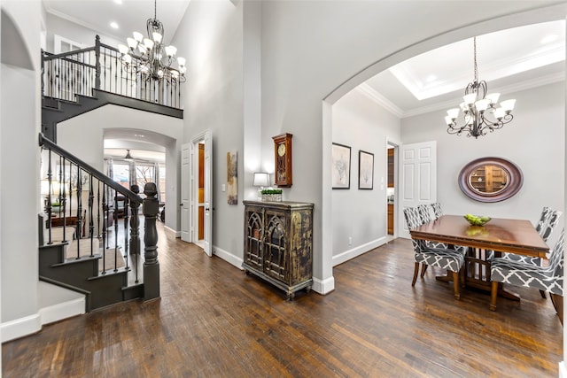 foyer with arched walkways, stairway, dark wood-style floors, and a notable chandelier