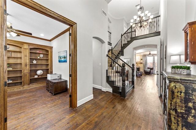 foyer entrance featuring arched walkways, dark wood-style flooring, visible vents, and ceiling fan with notable chandelier