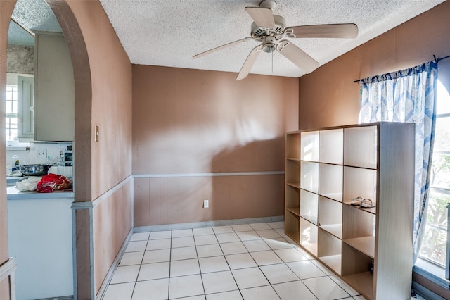 interior space with ceiling fan, a textured ceiling, and light tile patterned floors