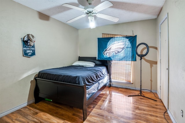 bedroom featuring ceiling fan, hardwood / wood-style floors, and a textured ceiling