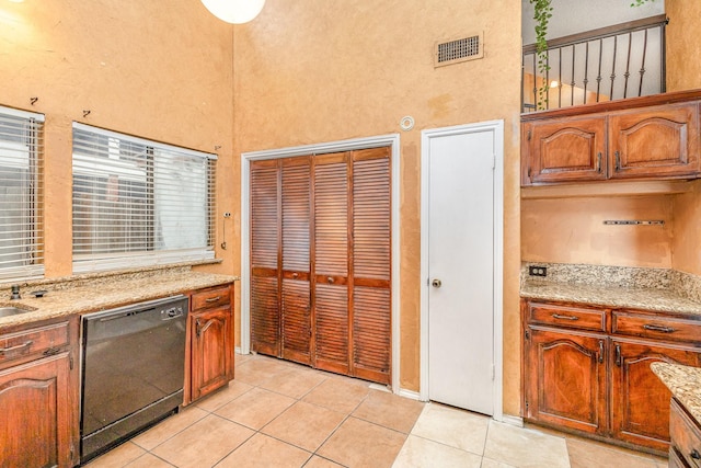 kitchen featuring dishwasher, light stone countertops, and light tile patterned floors