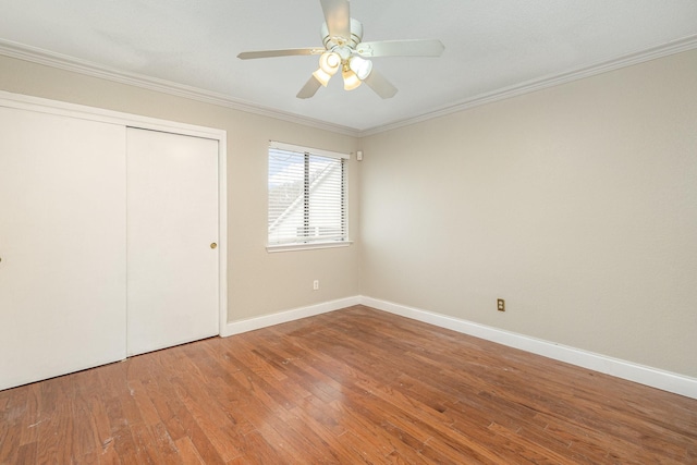 unfurnished bedroom featuring hardwood / wood-style flooring, ornamental molding, ceiling fan, and a closet