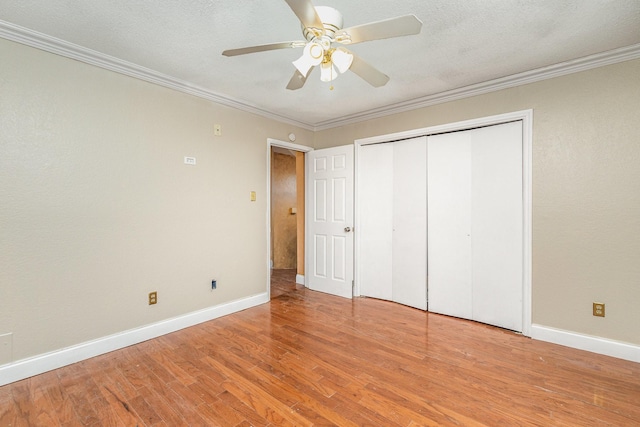 unfurnished bedroom with a textured ceiling, light hardwood / wood-style flooring, ornamental molding, a closet, and ceiling fan