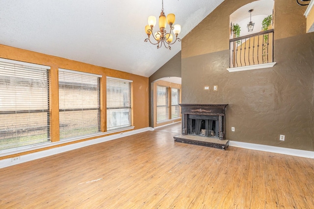 unfurnished living room featuring hardwood / wood-style flooring, lofted ceiling, and a notable chandelier