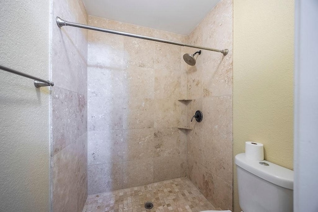 bathroom with a tile shower and toilet