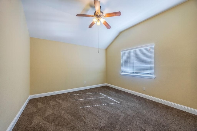 empty room with dark carpet, vaulted ceiling, and ceiling fan