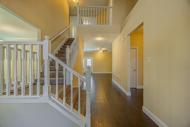 stairs with hardwood / wood-style flooring and a towering ceiling