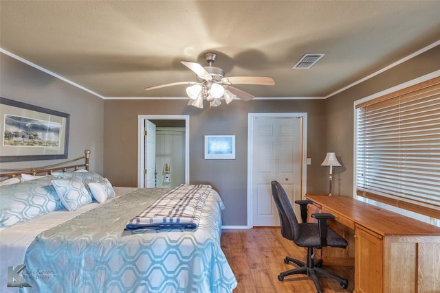 bedroom with baseboards, visible vents, light wood-style floors, a ceiling fan, and crown molding