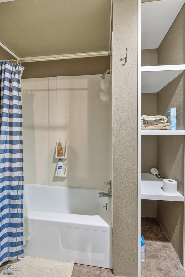 bathroom with a textured wall, shower / bath combo with shower curtain, and tile patterned floors