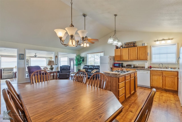 dining space featuring light wood-type flooring, ceiling fan with notable chandelier, lofted ceiling, and sink