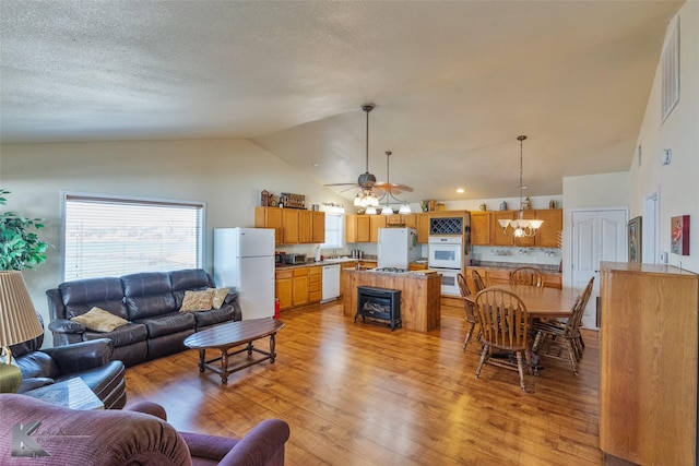 living area featuring light wood-type flooring, high vaulted ceiling, and ceiling fan with notable chandelier