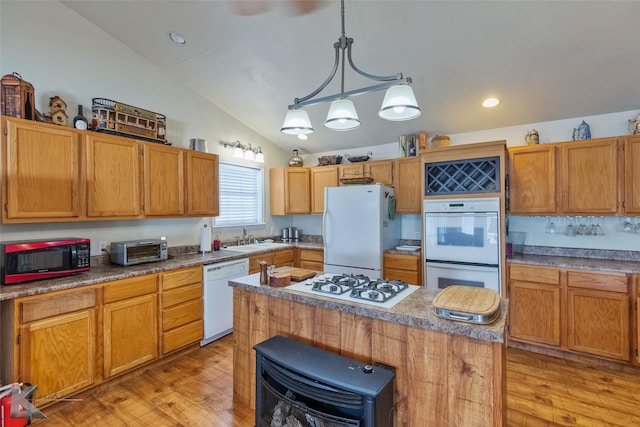 kitchen with decorative light fixtures, white appliances, a center island, and light hardwood / wood-style flooring