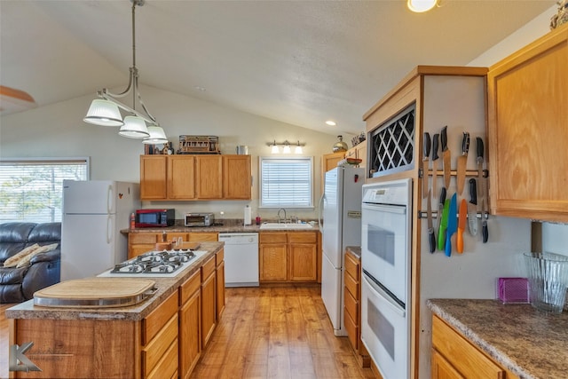 kitchen with brown cabinets, lofted ceiling, light wood finished floors, a sink, and white appliances