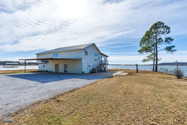 view of side of home featuring a water view, a carport, and a yard